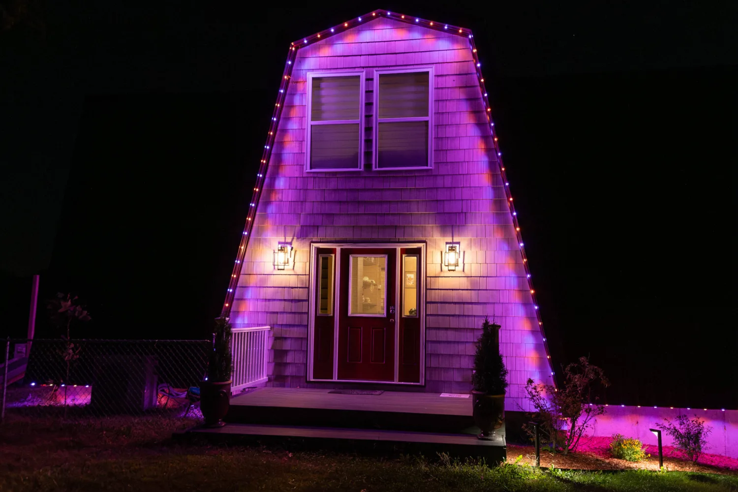 barn-style home with purple, blue and red permanent holiday lights