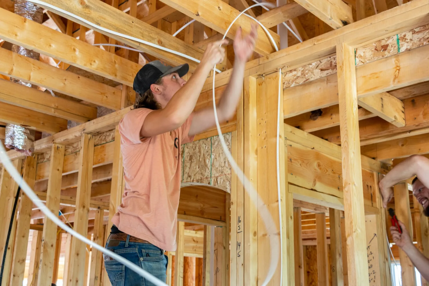 Electrician pulling wire through new framing Electrician pulling wire through the framing of a new home