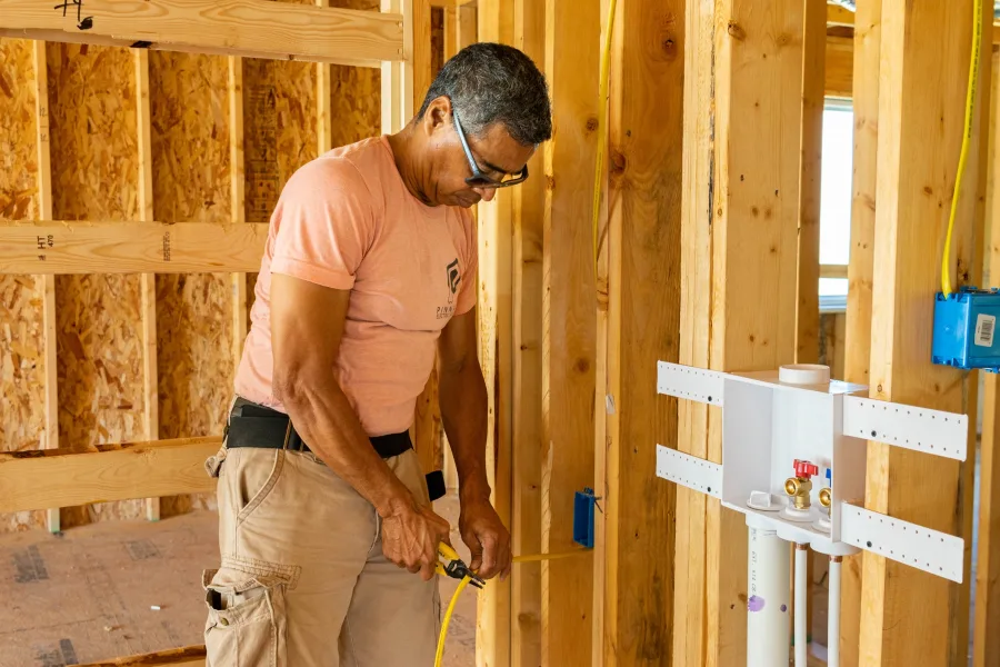 Electrician wiring an outlet box in a framed wall